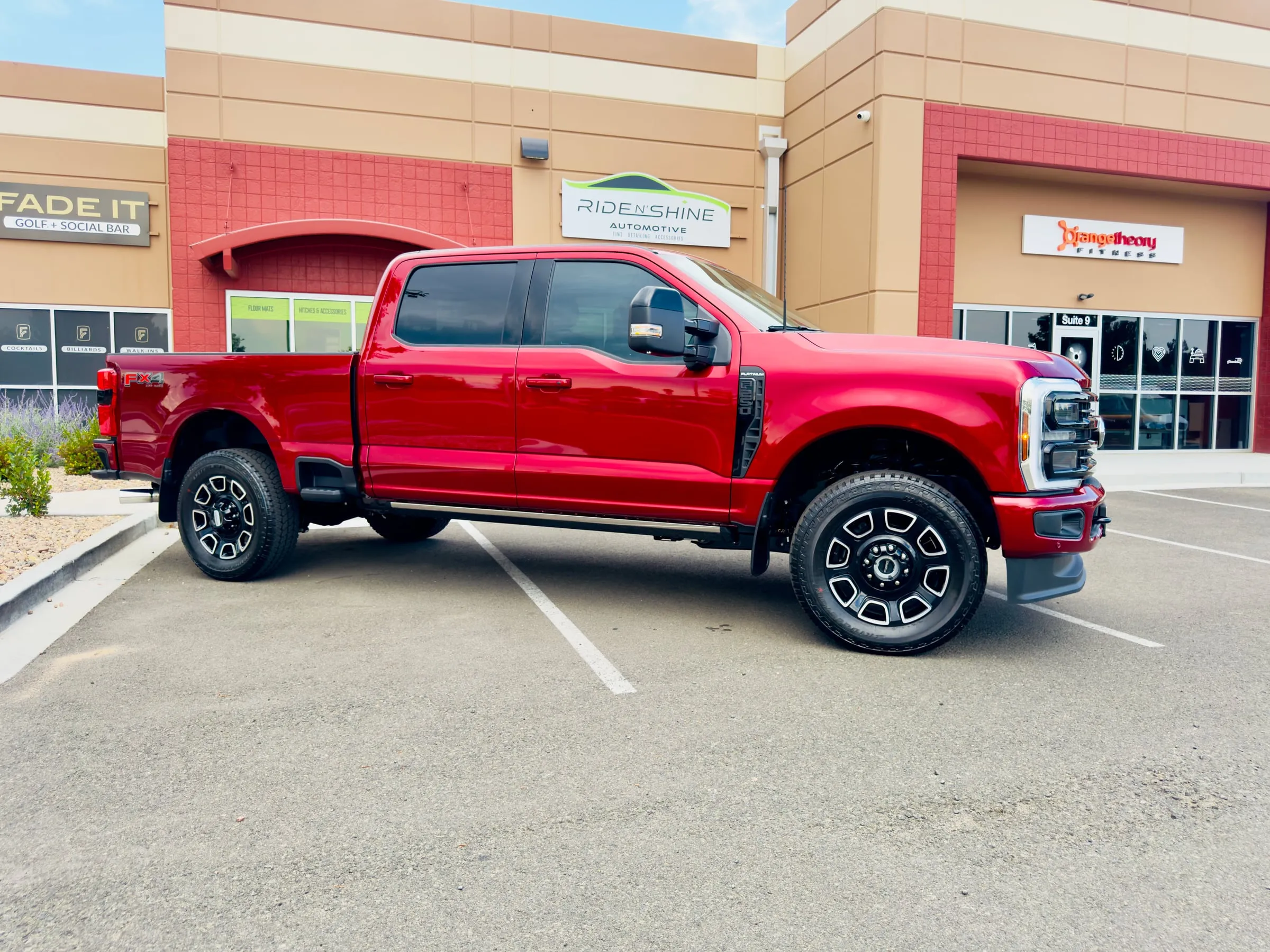 A red Ford F-250 Super Duty Platinum in side profile outside the Ride N' Shine storefront in Arvada